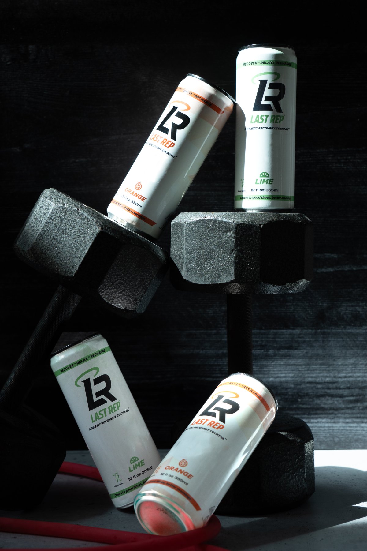Last Rep Orange and Lime cans resting on dumbbells in a gym